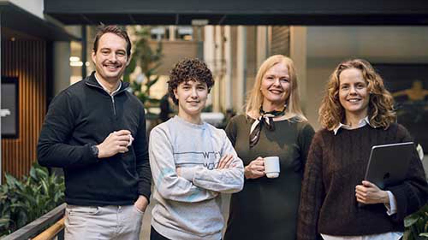 Fire personer står sammen og smiler