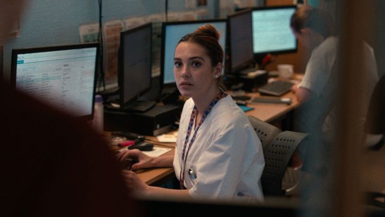 Bildet viser karakteren Petra fra NRK-serien LIS som sitter ved en kontorpult. Hun kikker på en person som står utenfor bildeutsnittet.