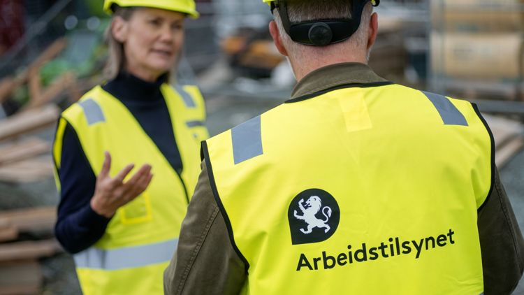 Bildet viset to inspektører med gul vest som er på tilsyn på en byggeplass.